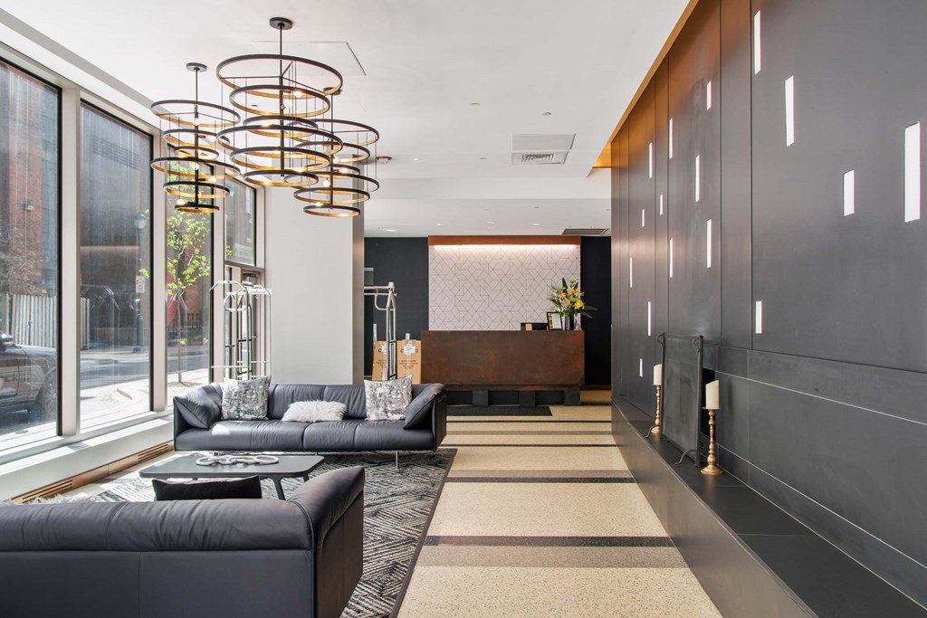 A modern living room with a long black couch and a circular chandelier.
