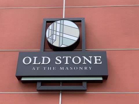 A sign for Old Stone at the Masonry is mounted on a wall.