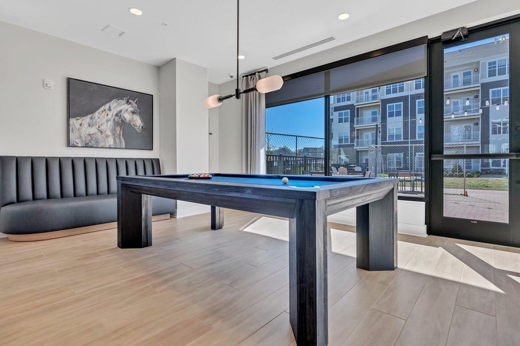 A pool table in a room with a view of a building outside the window.