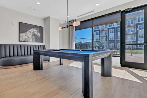 A pool table in a room with a view of a building outside the window.