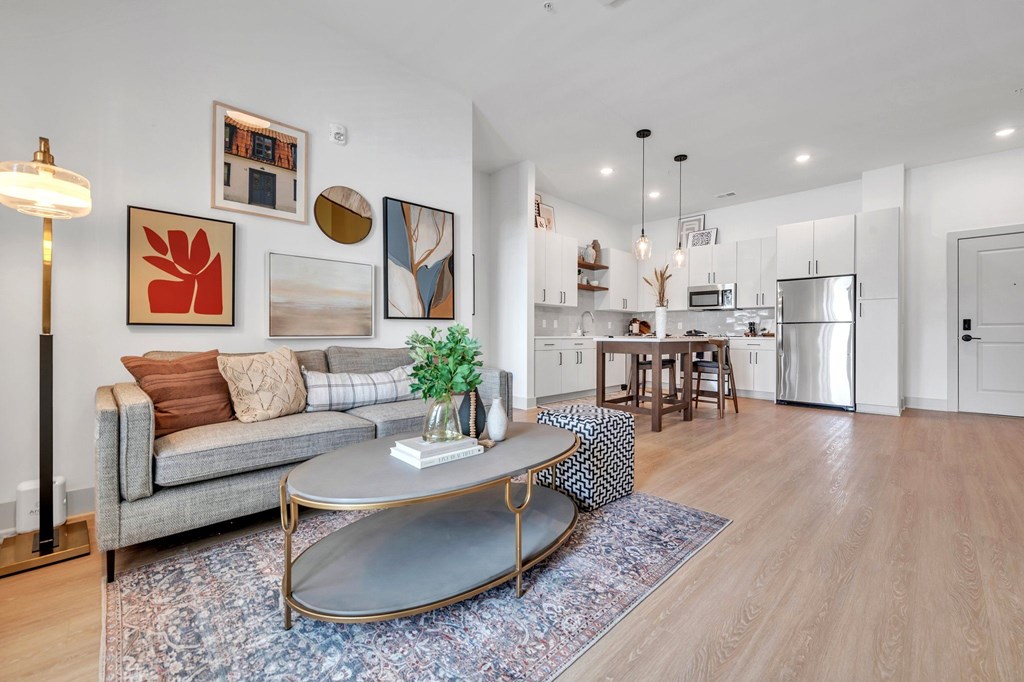 A modern living room with a grey sofa, a coffee table, and a kitchen in the background.