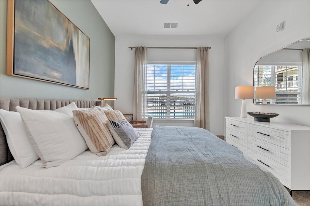 A bedroom with a large bed and a painting on the wall.