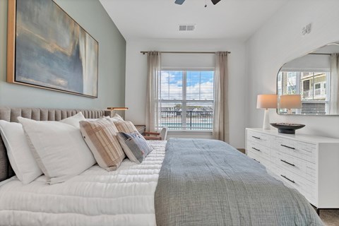 A bedroom with a large bed and a painting on the wall.