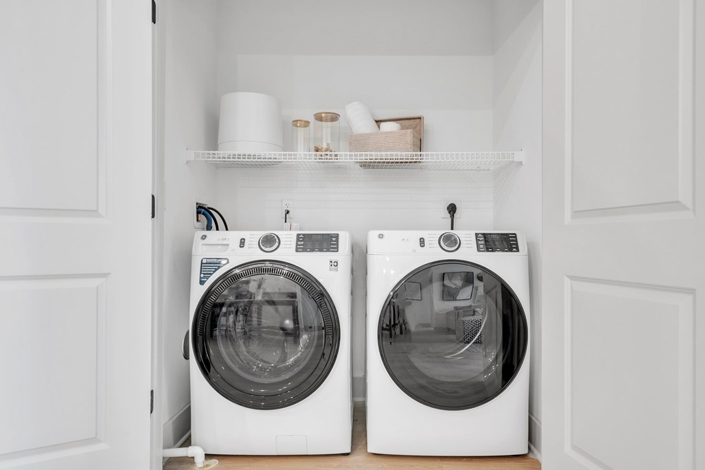 Two white front load washing machines in a laundry room.