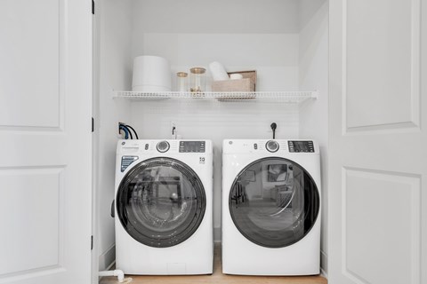 Two white front load washing machines in a laundry room.