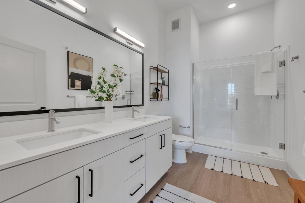 A white bathroom with a sink, mirror, and toilet.