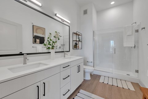 A white bathroom with a sink, mirror, and toilet.