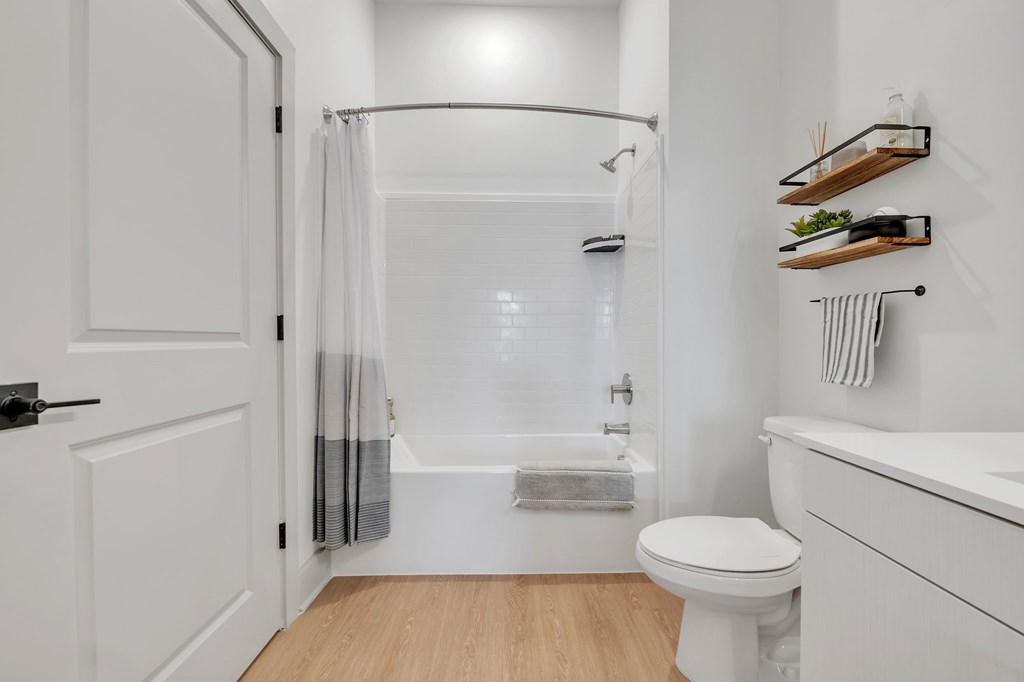 A white bathroom with a toilet, sink, and shower.