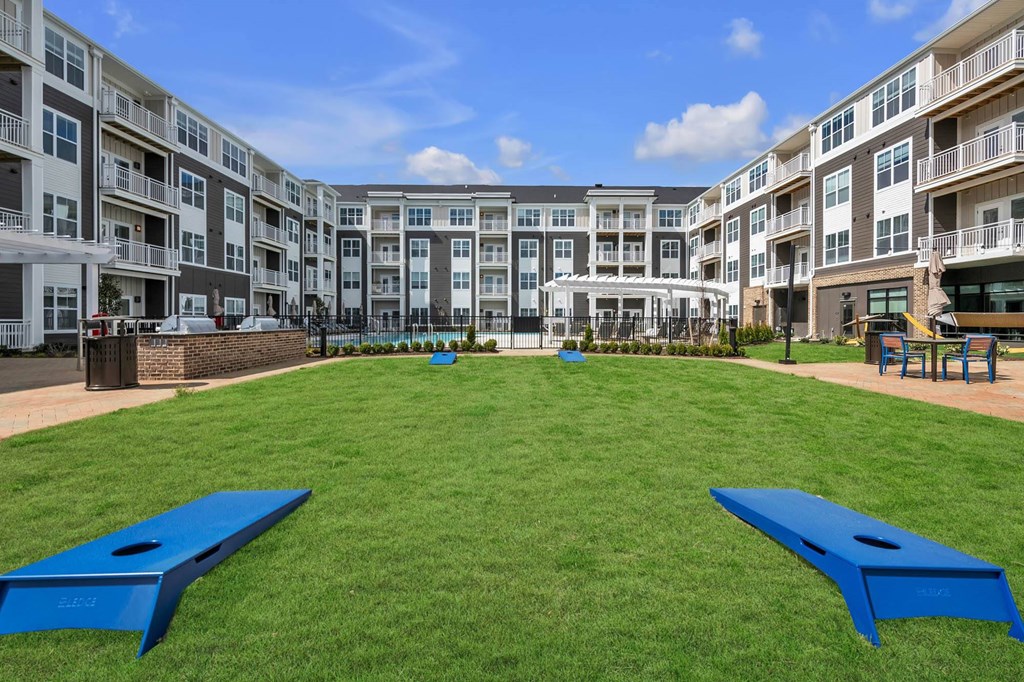 A large grassy area with two blue benches in front of apartment buildings.