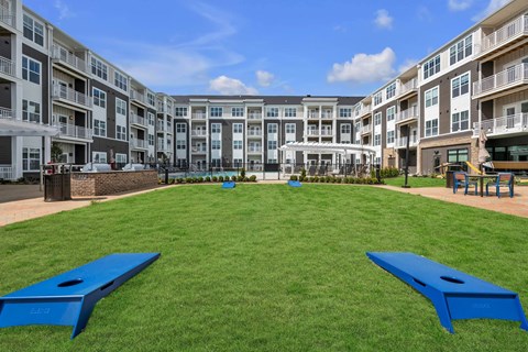 A large grassy area with two blue benches in front of apartment buildings.
