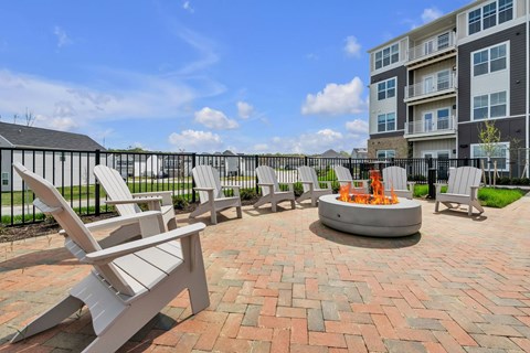 A patio with chairs and a fire pit in front of a building.