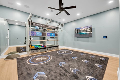 A room with a grey carpet and a black ceiling fan.