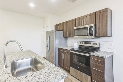 A kitchen with a sink, stove, oven, and microwave.