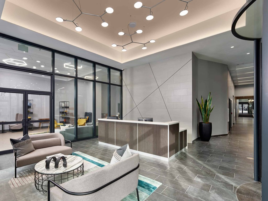 A modern office lobby with a glass wall and a grey sofa.