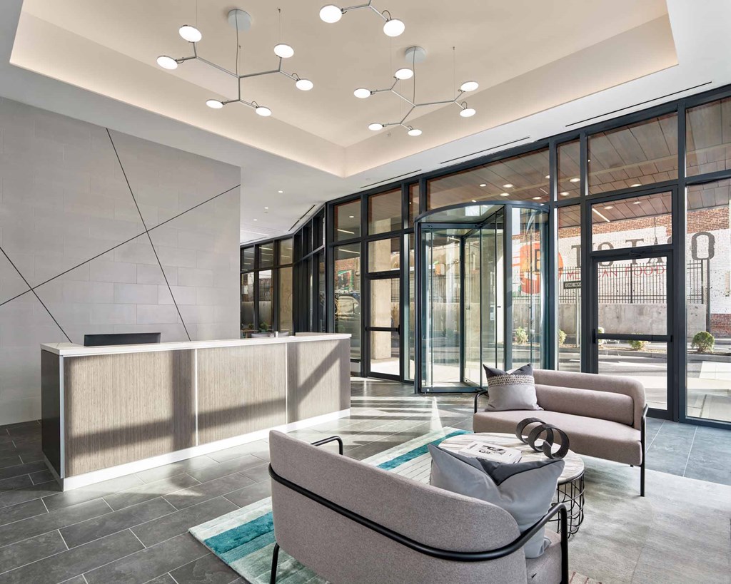 A modern office lobby with a reception desk and a seating area.
