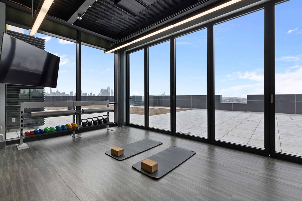 A yoga studio with a view of the cityscape outside the large windows.