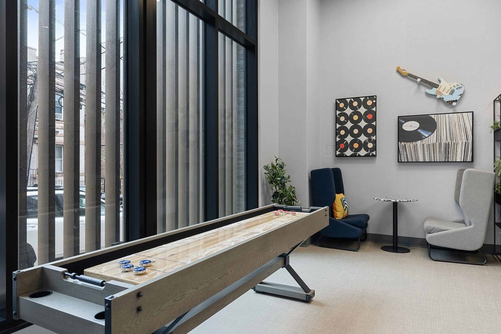 A pool table in a room with a chair, a plant, and pictures on the wall.