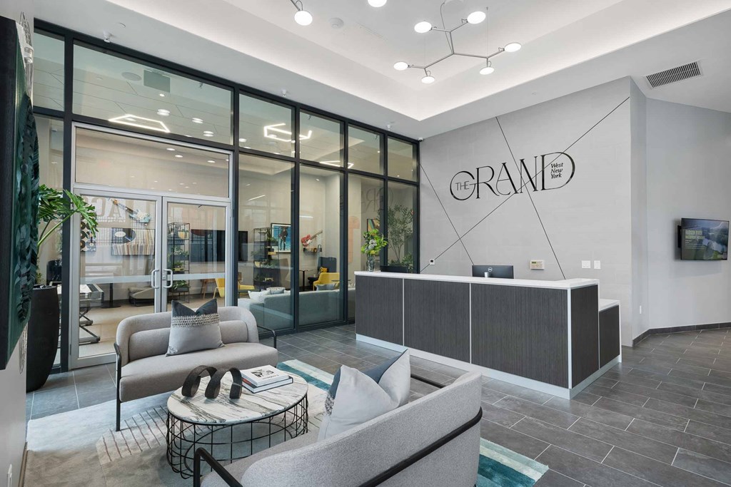 A modern office lobby with a reception desk and a large glass wall.