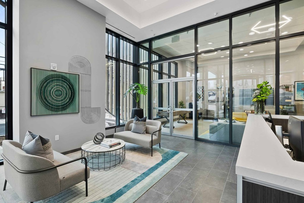 A modern living room with a large artwork on the wall and a glass door leading to another room.