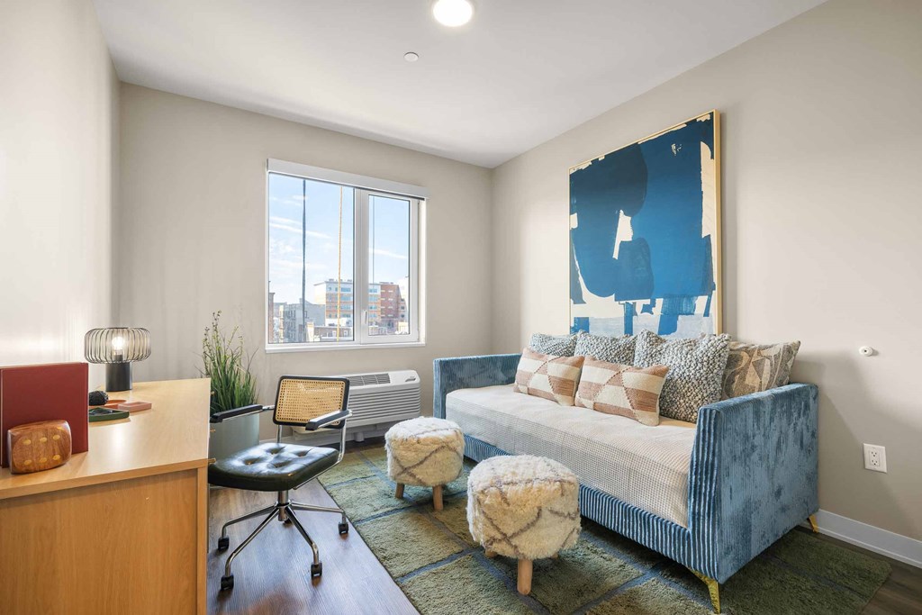 A blue couch with pillows sits in a room with a large window.