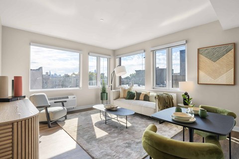 A living room with a green chair and a table with a vase of flowers on it.