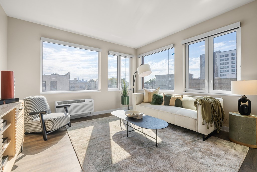 A living room with a white couch, a chair, a table, and a floor lamp.