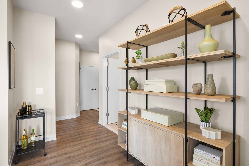 A room with a shelf and a cart holding bottles.