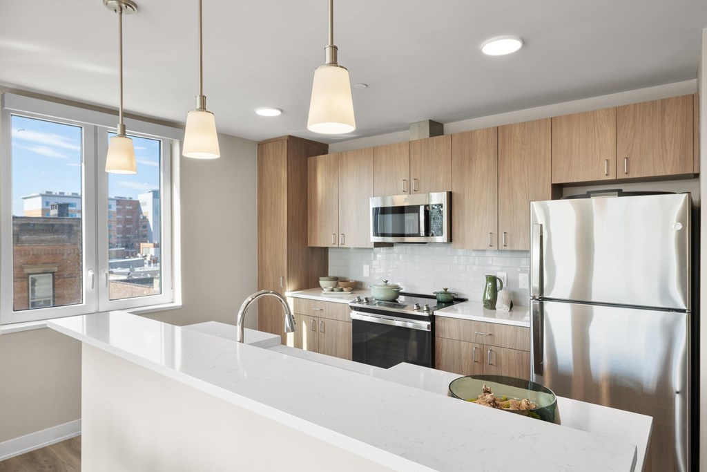 A kitchen with a white counter top and wooden cabinets.