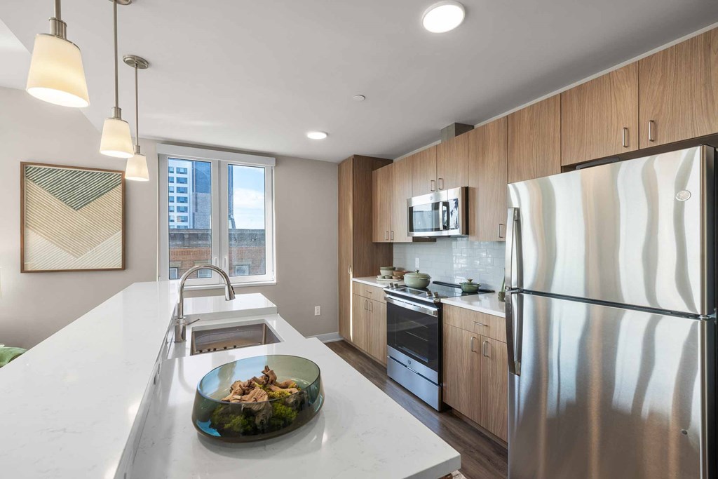 A modern kitchen with a stainless steel refrigerator and a marble countertop.