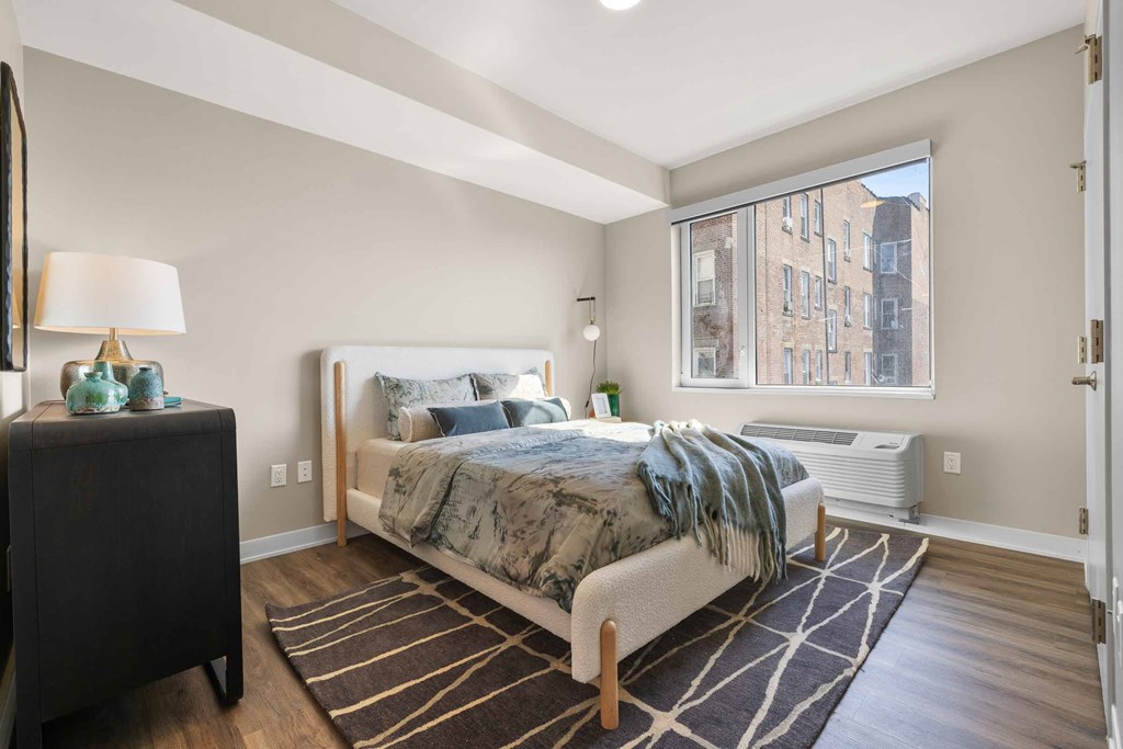 A bedroom with a large bed and a window overlooking a city.