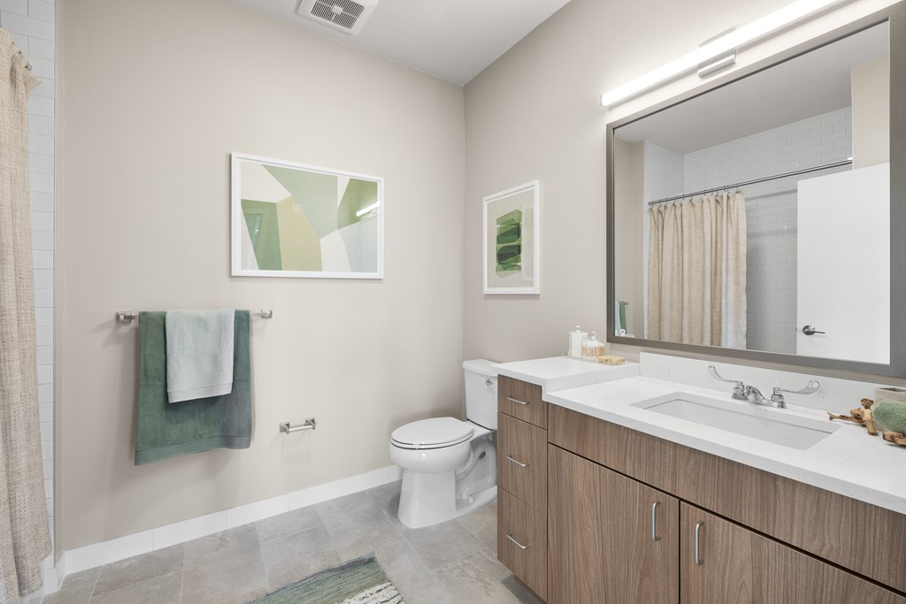 A bathroom with a toilet, sink, and mirror.