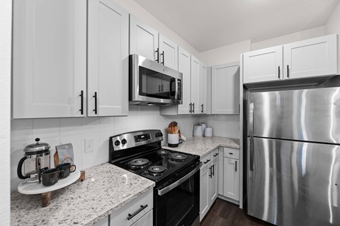 A kitchen with white cabinets and a stainless steel refrigerator.