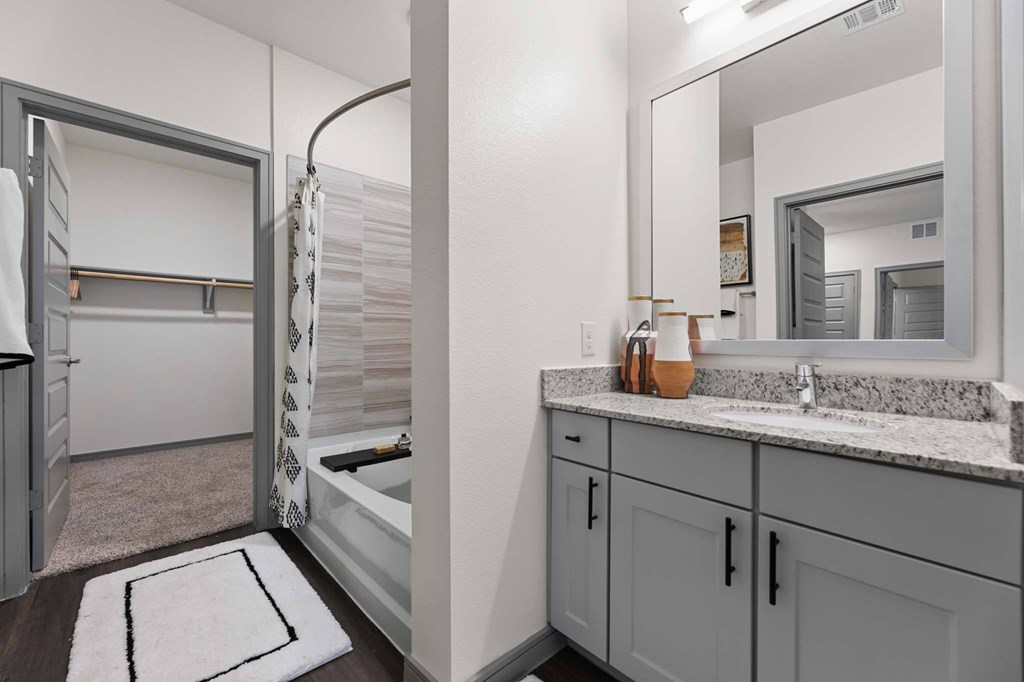 A bathroom with a sink, mirror, and bathtub.