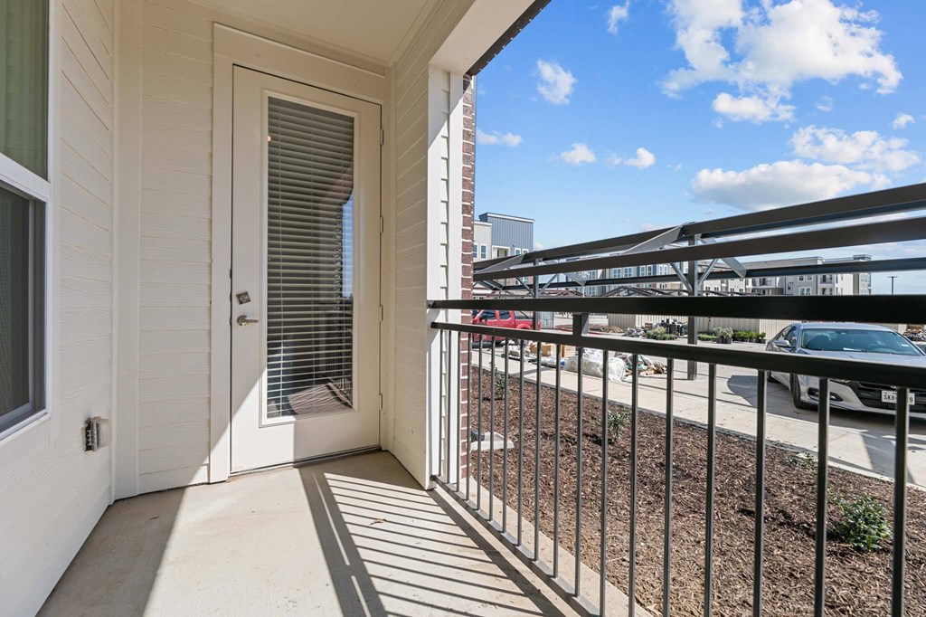 A balcony with a metal railing and a view of the street below.