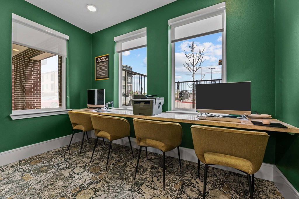 A room with green walls has a long table with chairs and a laptop on it.