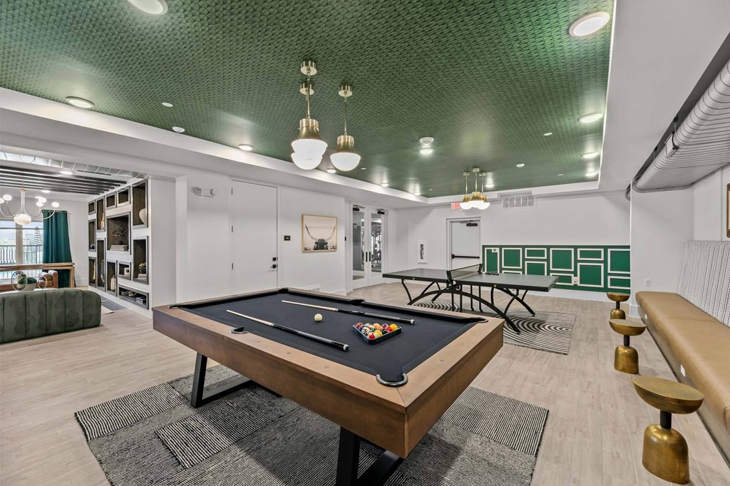 A pool table is in the middle of a room with a green ceiling.