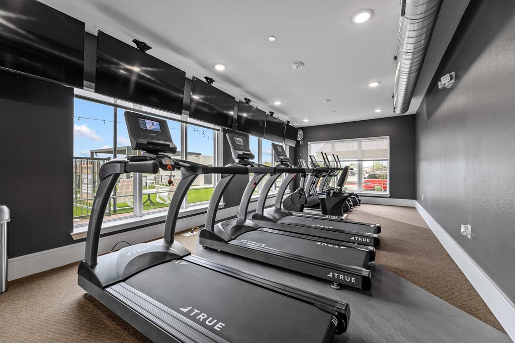 A row of TRUE treadmills are lined up in a gym.
