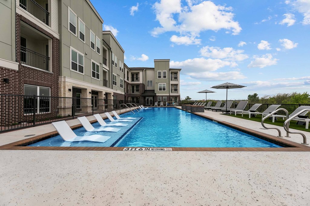 A pool surrounded by chairs and buildings.