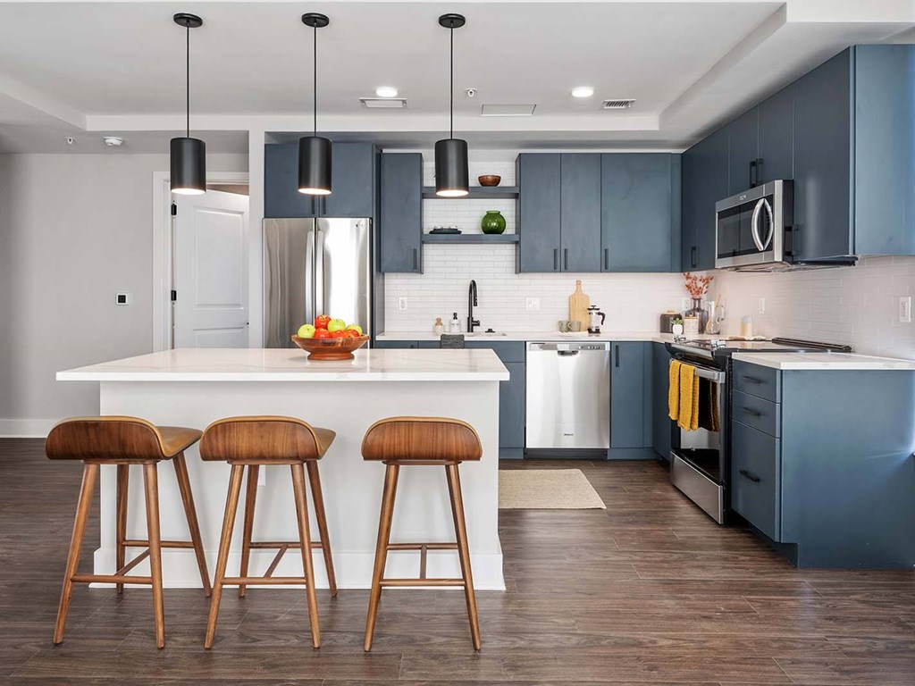 A kitchen with a white island and brown bar stools.