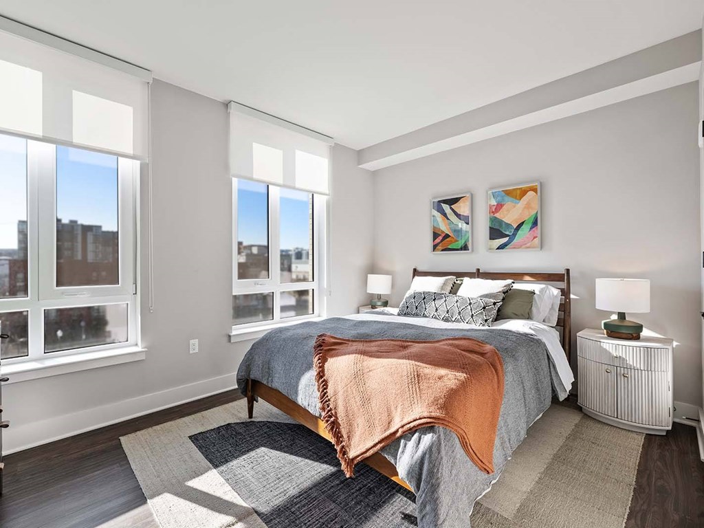 A bedroom with a large bed and a view of the city through the windows.
