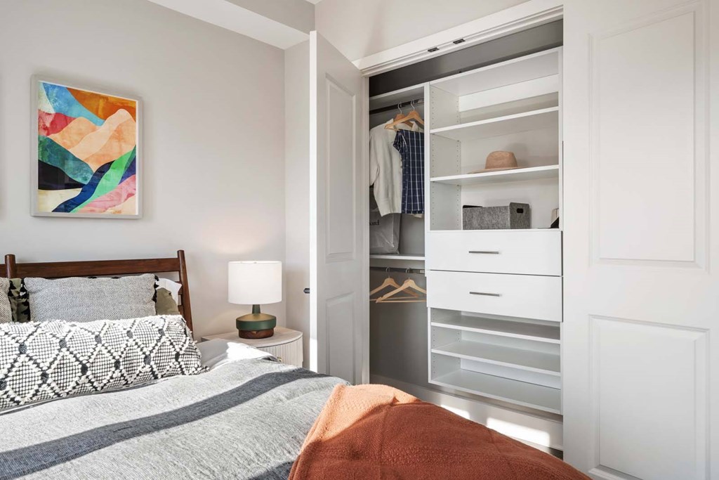 A bedroom with a bed, nightstand, and a painting on the wall.