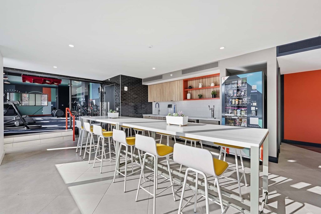 A long white table with yellow chairs is in the middle of the room.