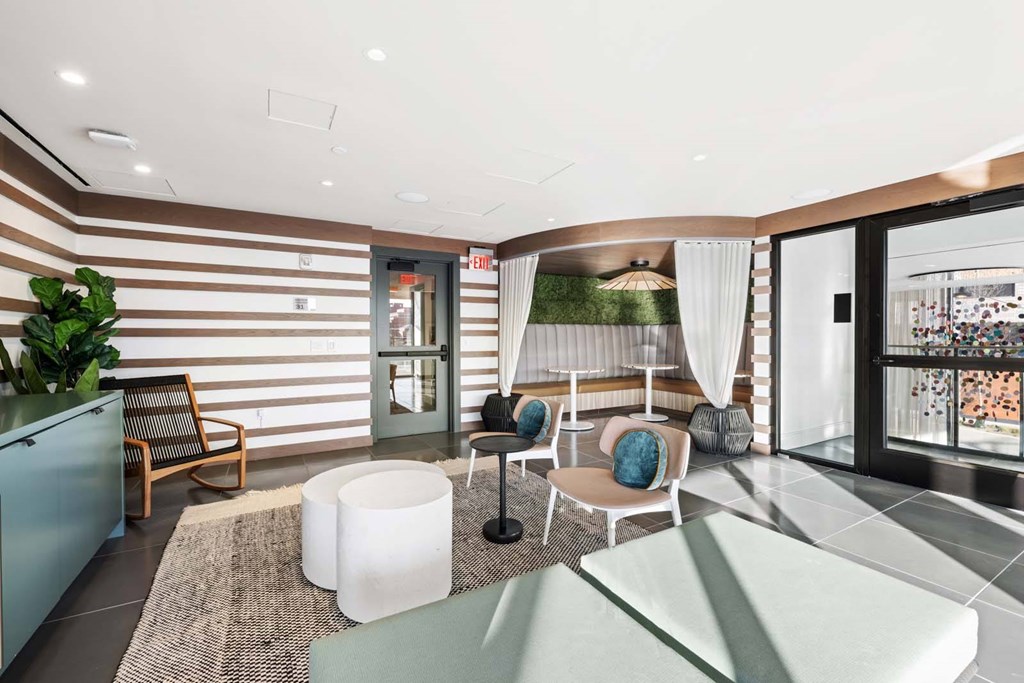 A modern living room with a striped wallpaper and a glass door leading to a balcony.