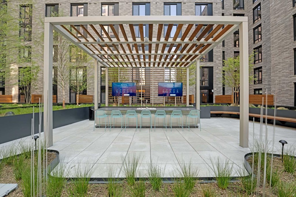 A modern outdoor seating area with a wooden pergola and blue chairs.