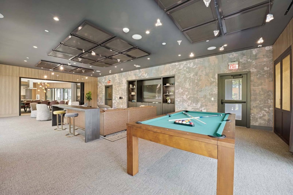 A room with a pool table and a bar area.
