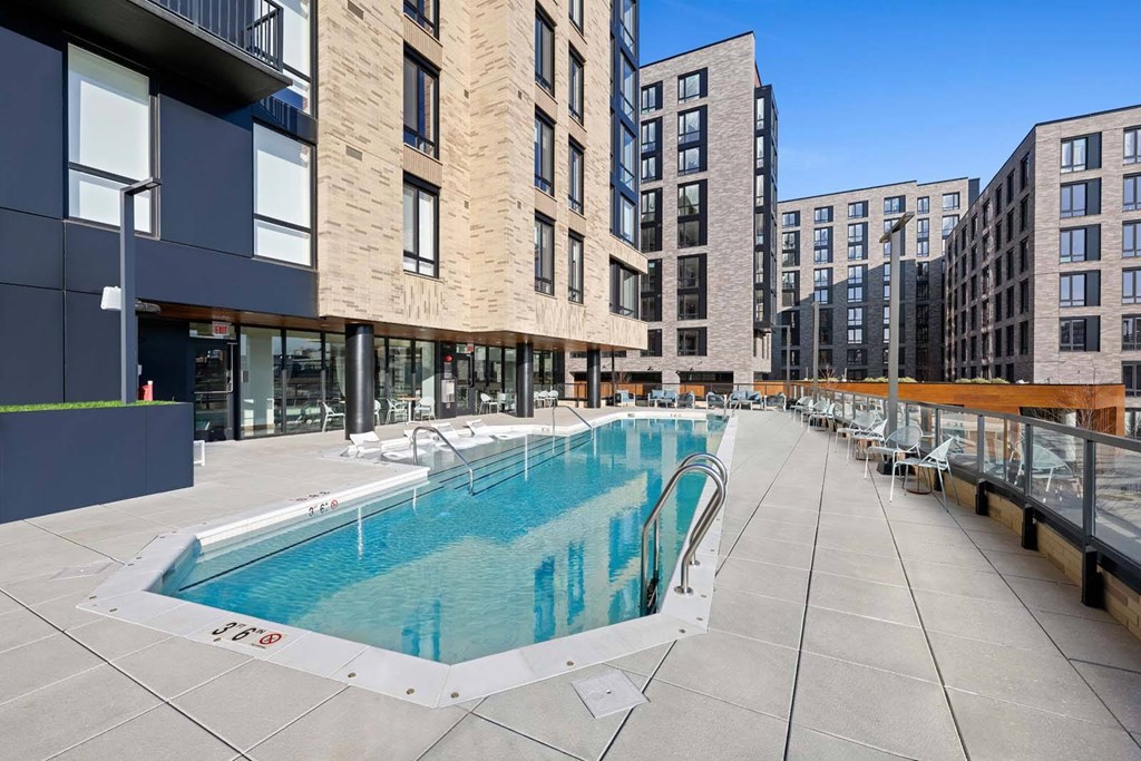 A swimming pool is surrounded by apartment buildings.