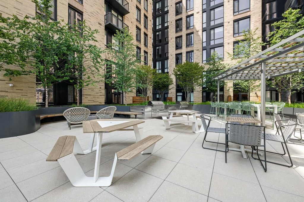 A patio with tables and chairs is surrounded by buildings.