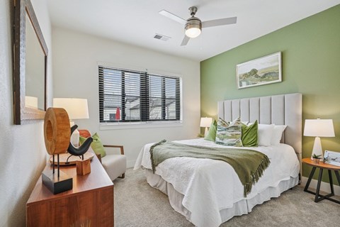 A bedroom with a large bed and a ceiling fan.