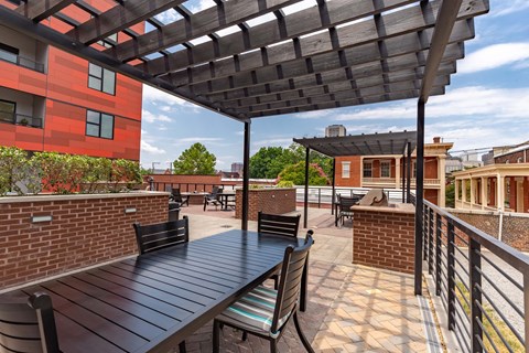 A patio with a black table and chairs under a wooden pergola.
