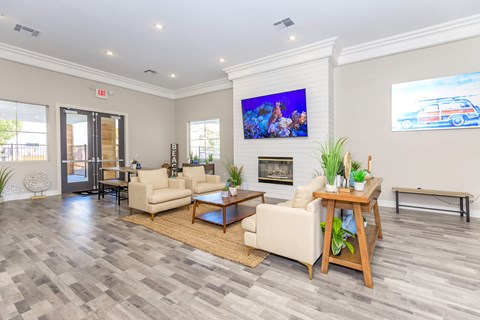 A living room with a grey floor and a white wall with a painting on it.